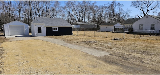 view of yard featuring driveway, a detached garage, an outdoor structure, and fence