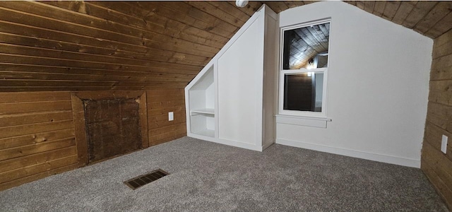 bonus room featuring wooden walls, visible vents, vaulted ceiling, wooden ceiling, and dark colored carpet