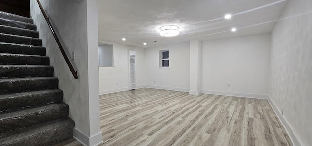 finished below grade area featuring stairway, recessed lighting, wood finished floors, and baseboards