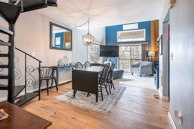 dining room featuring stairway, baseboards, hardwood / wood-style flooring, a wall mounted air conditioner, and a textured ceiling