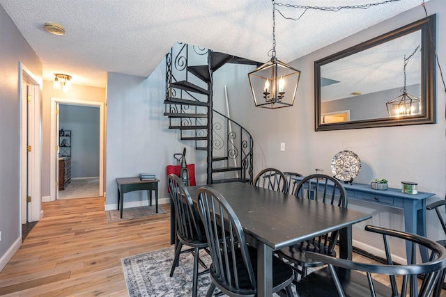 dining area with stairway, baseboards, light wood-style floors, a textured ceiling, and a chandelier