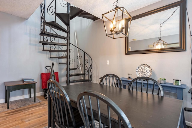 dining area featuring stairway, baseboards, light wood-style floors, a textured ceiling, and a notable chandelier