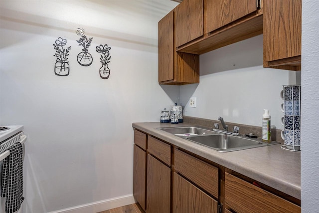 kitchen featuring brown cabinetry, baseboards, and a sink