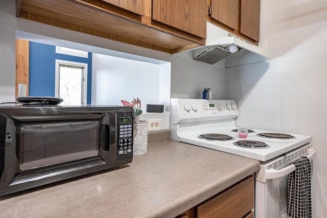 kitchen featuring electric stove, under cabinet range hood, brown cabinetry, a toaster, and light countertops