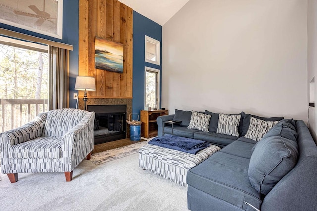 living area with high vaulted ceiling, a glass covered fireplace, and carpet