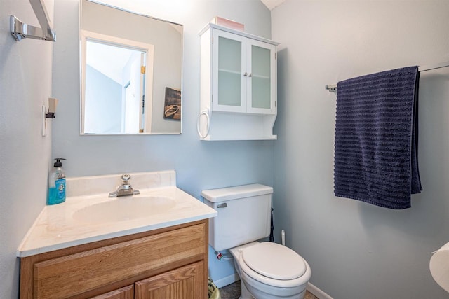 half bath featuring toilet, vanity, and baseboards