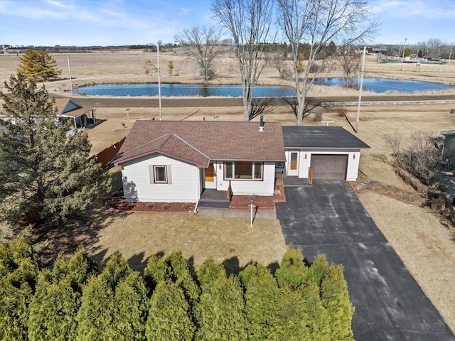 view of front facade featuring aphalt driveway, a garage, a water view, and roof with shingles