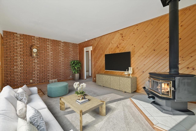 living area with wooden walls, carpet, visible vents, brick wall, and a wood stove