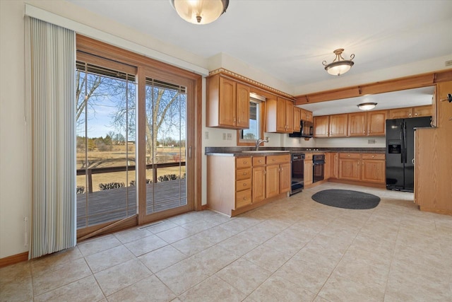 kitchen featuring visible vents, black appliances, a sink, dark countertops, and baseboards