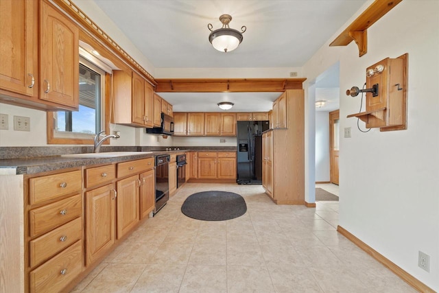 kitchen featuring dark countertops, baseboards, light tile patterned flooring, black appliances, and a sink