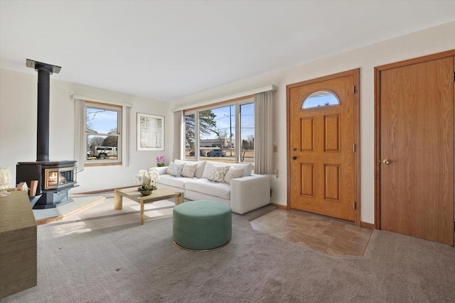 carpeted living room featuring a wood stove and baseboards