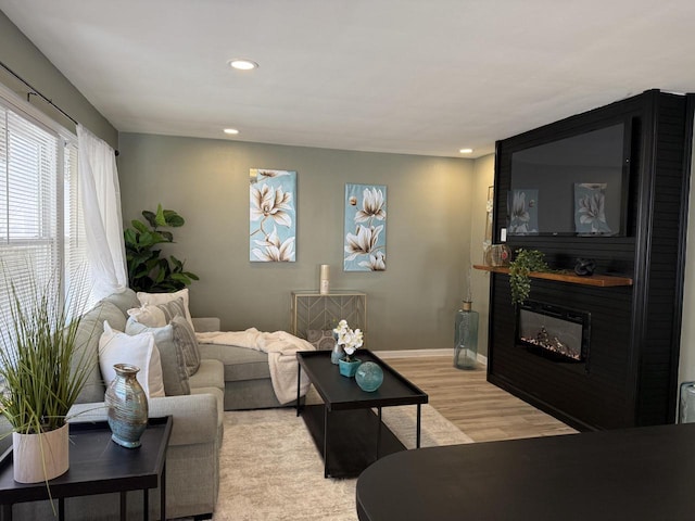 living room with light wood-style floors, recessed lighting, baseboards, and a large fireplace