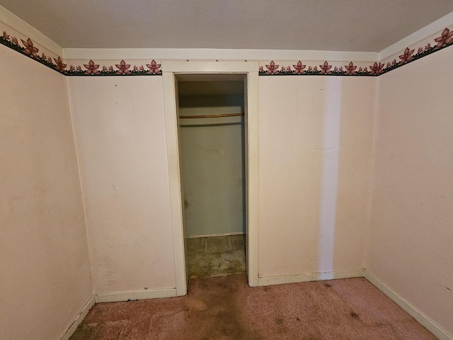 unfurnished bedroom with baseboards, carpet floors, and a closet