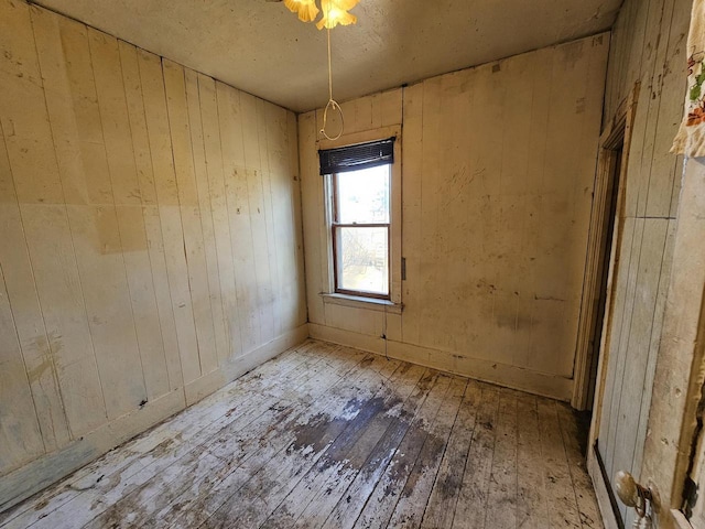 spare room with wooden walls and wood-type flooring