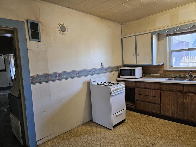 kitchen featuring light floors, white appliances, light countertops, and a sink