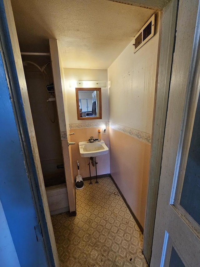 bathroom featuring tile patterned floors, visible vents, a sink, a textured ceiling, and a shower