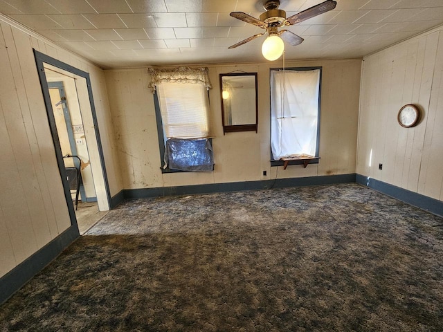 empty room with carpet floors, wooden walls, and a healthy amount of sunlight