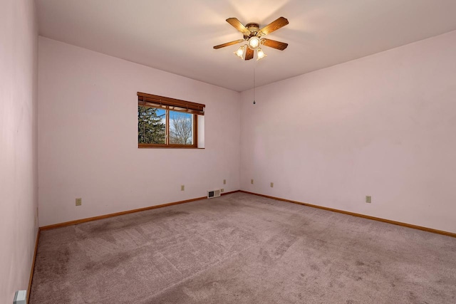 carpeted empty room with a ceiling fan, visible vents, and baseboards