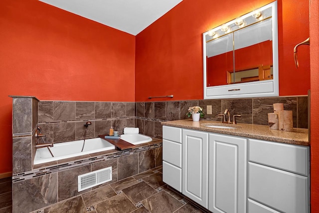 bathroom with vanity, a garden tub, and visible vents