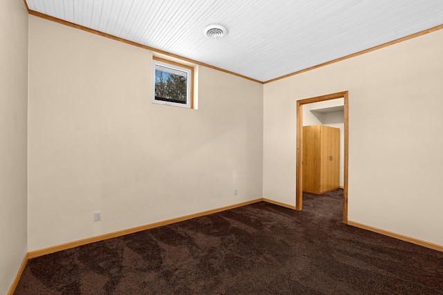 empty room with visible vents, baseboards, wood ceiling, ornamental molding, and dark colored carpet