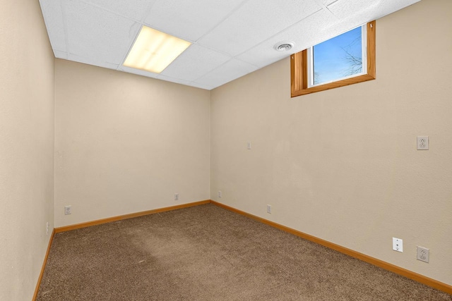 below grade area featuring a paneled ceiling, carpet, visible vents, and baseboards