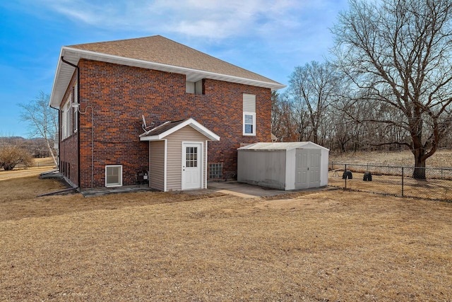 back of property with brick siding, fence, a yard, an outbuilding, and a storage unit