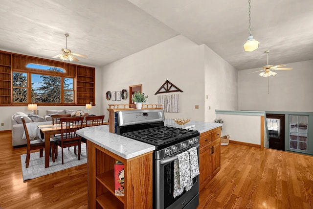 kitchen featuring open floor plan, brown cabinets, light wood-style floors, gas stove, and a ceiling fan