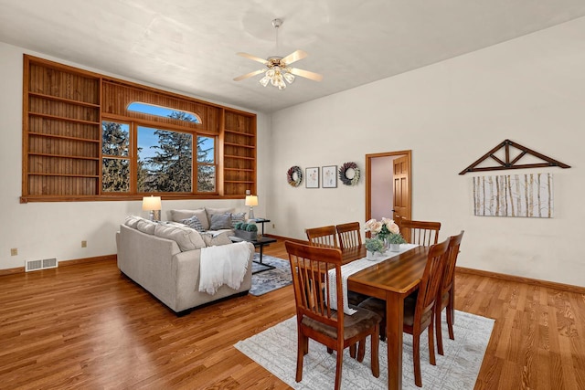 dining area featuring visible vents, baseboards, a ceiling fan, and light wood finished floors