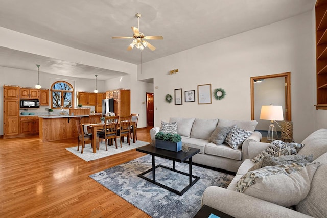 living area with light wood-type flooring and ceiling fan