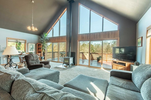 carpeted living room with a notable chandelier, high vaulted ceiling, and a wood stove