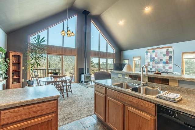 kitchen with a wood stove, a sink, black dishwasher, pendant lighting, and carpet flooring