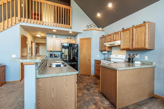 kitchen featuring under cabinet range hood, a peninsula, freestanding refrigerator, white electric range oven, and a sink