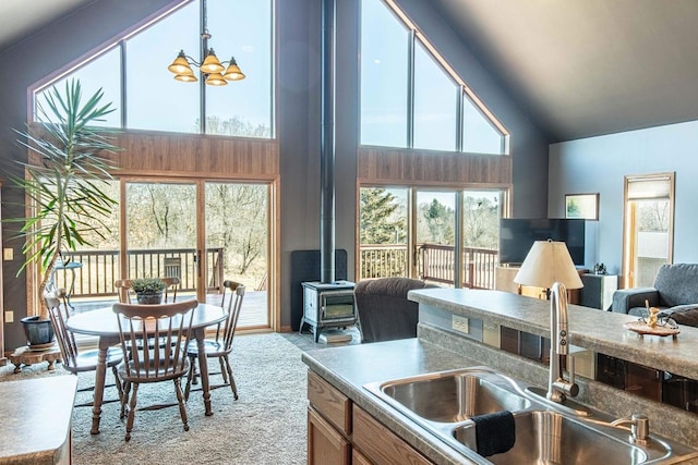 kitchen featuring a sink, high vaulted ceiling, open floor plan, and a wood stove