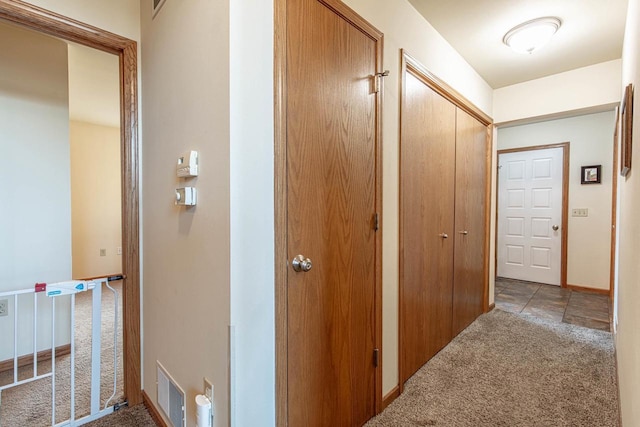 hall featuring visible vents, baseboards, and light colored carpet