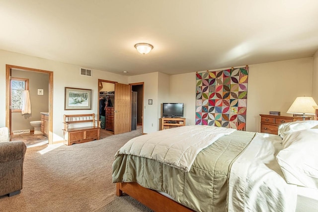 bedroom with a spacious closet, visible vents, baseboards, carpet, and ensuite bath