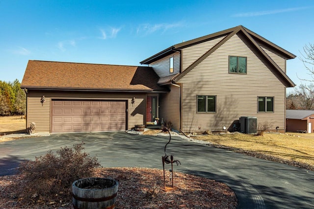 traditional-style house with driveway, central AC, and a garage