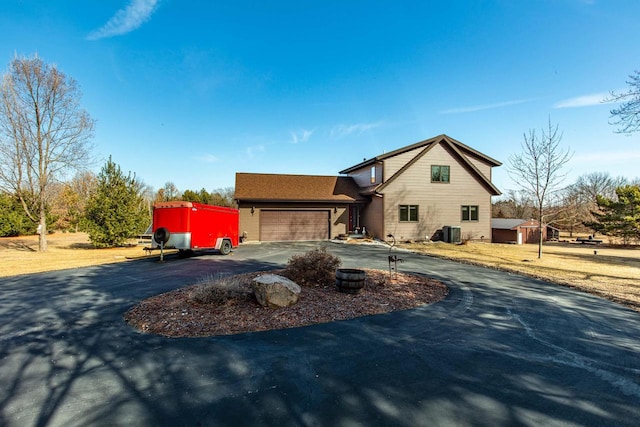 view of front facade featuring central AC unit, a garage, and curved driveway