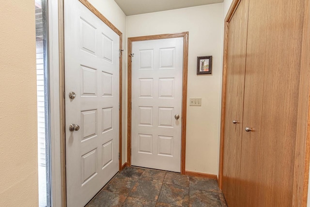 foyer with stone finish floor and baseboards