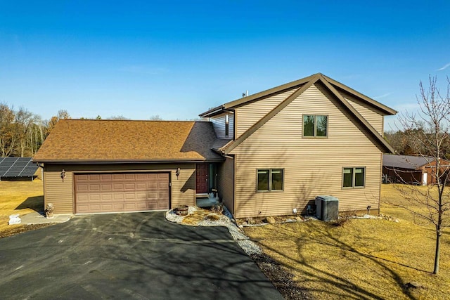 view of front of home featuring central air condition unit, a garage, and aphalt driveway