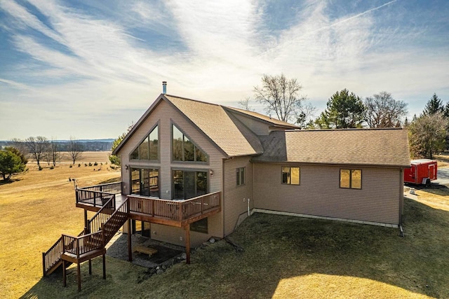 rear view of house featuring a deck, stairway, a lawn, and a shingled roof