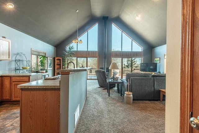 kitchen featuring open floor plan, pendant lighting, brown cabinets, high vaulted ceiling, and dark colored carpet