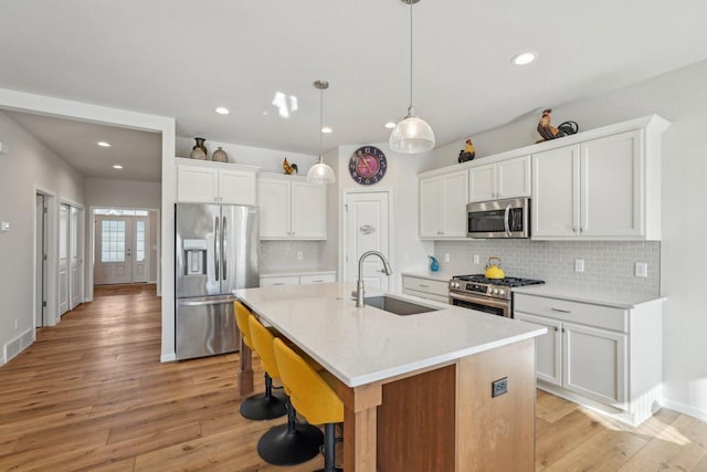 kitchen featuring white cabinetry, stainless steel appliances, light wood-style floors, and a sink