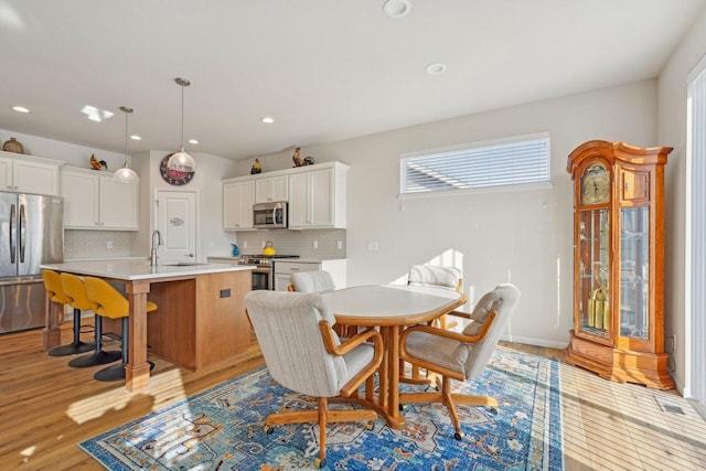 dining room with recessed lighting, light wood-type flooring, and baseboards