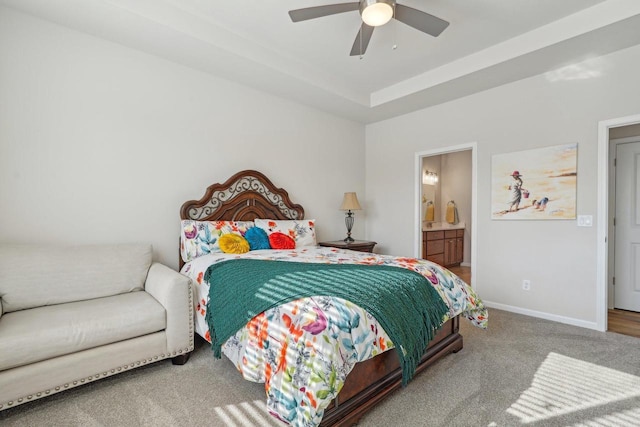 bedroom with a ceiling fan, baseboards, carpet floors, ensuite bathroom, and a raised ceiling