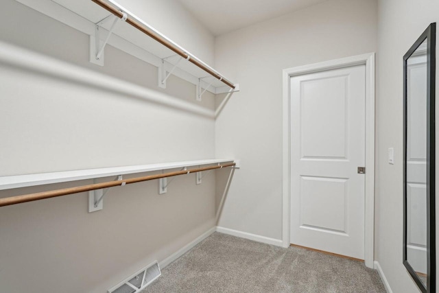 walk in closet with visible vents and light colored carpet