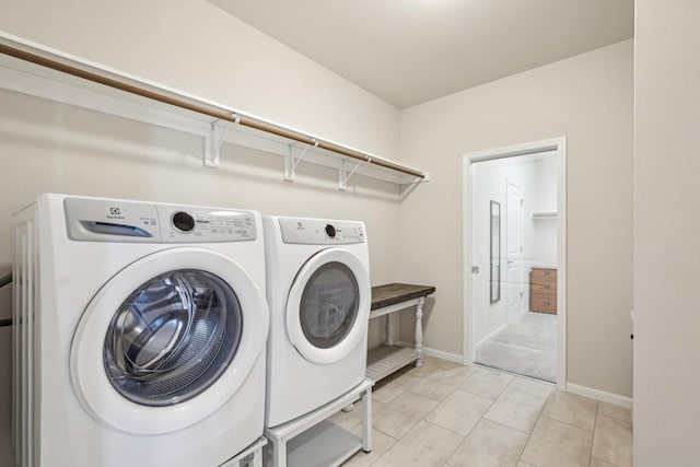 clothes washing area with light tile patterned floors, laundry area, independent washer and dryer, and baseboards