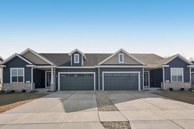 craftsman-style house with stone siding, an attached garage, driveway, and a shingled roof