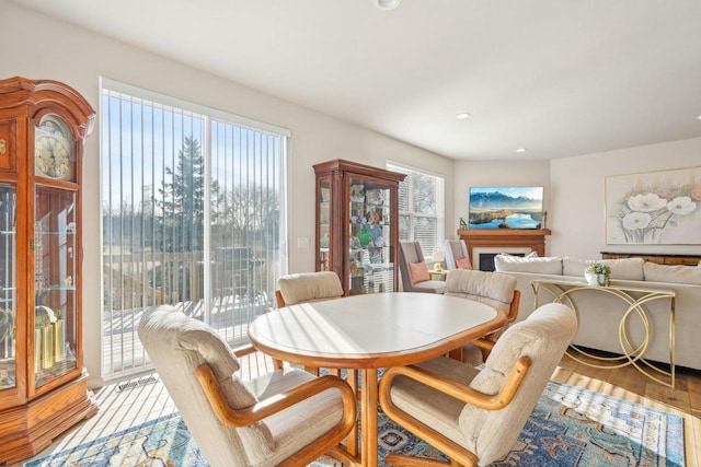 dining space with recessed lighting, a fireplace, and light wood finished floors