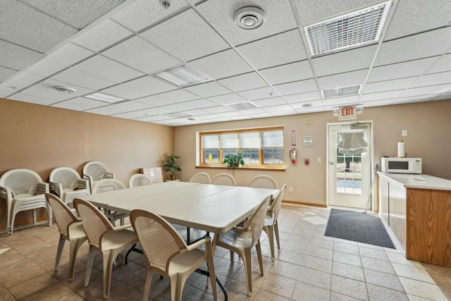 dining space featuring light tile patterned flooring, visible vents, a paneled ceiling, and baseboards