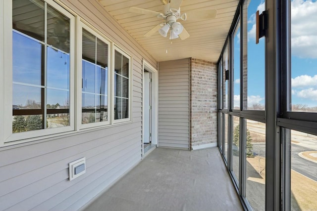 unfurnished sunroom featuring wood ceiling and a ceiling fan